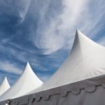 row of white event and party tents against blue sky